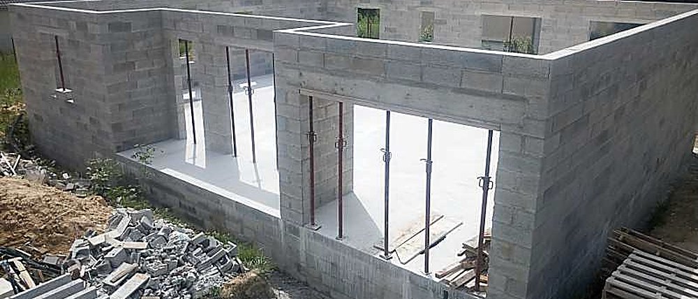 Maison individuelle en cours de construction : murs en blocs béton, linteaux étayés et dalle coulée