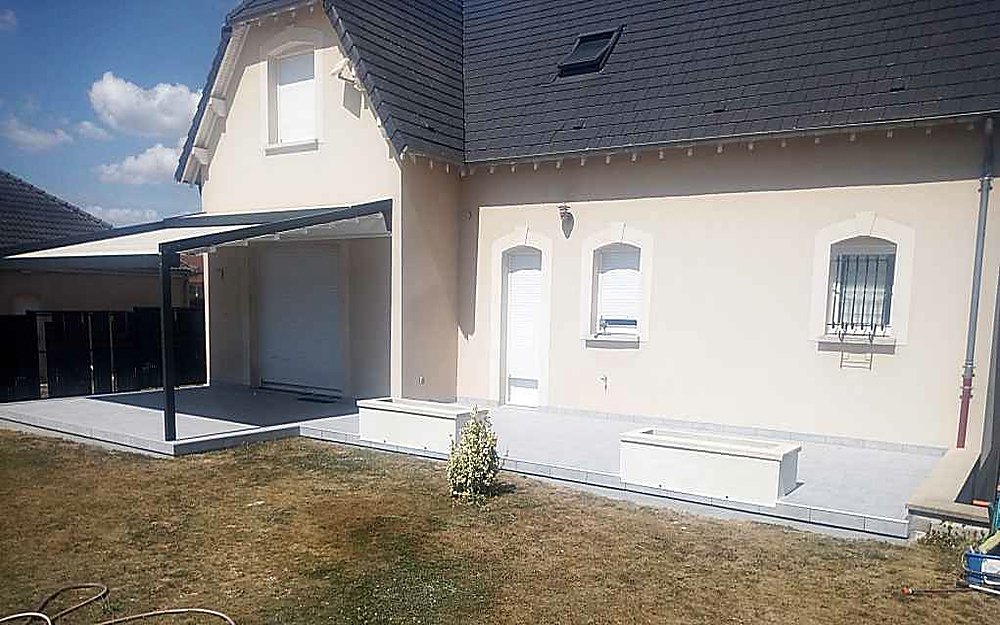 Terrasse en béton réalisée sous un auvent, le long d'une maison contemporaine